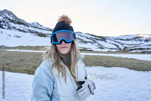 Obraz pretty girl looks at the camera with a casual and calm appearance equipped with a hat and snow goggles