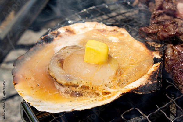 Obraz ホタテ貝にバターを乗せて 炭火 バーベキューで焼いている風景