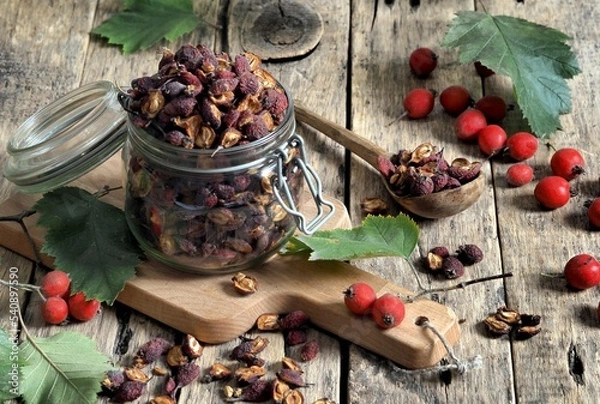 Fototapeta Tea with fresh and dried hawthorn berries in a glass cup on a wooden ancient background. Medicinal soothing herbal tea. Alternative medicine concept.