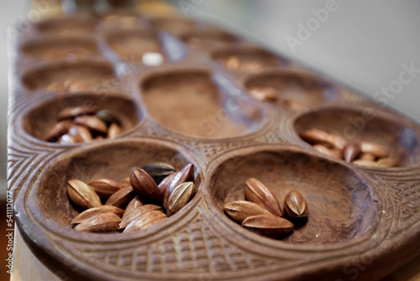 Fototapeta A hand carved Pallanguzhi game board contains seeds which are used as game pieces.