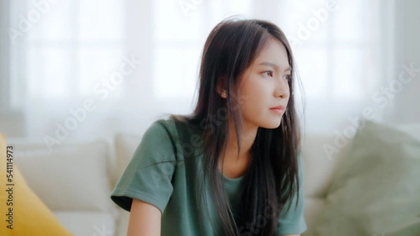 Obraz Upset asian woman frustrated by problem with work or relationships, sitting on couch, feeling despair and anxiety, loneliness, having psychological trouble