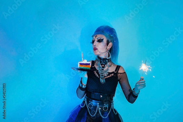 Obraz Goth girl blows out the candles on the cake and holds sparklers