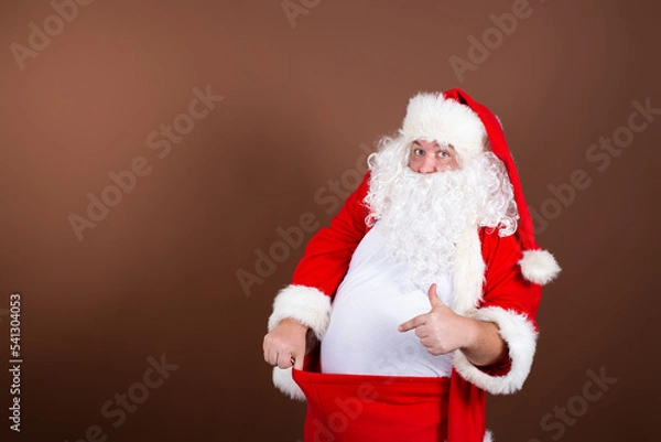 Obraz Men's health problems. Funny fat Santa Claus. Brown background.