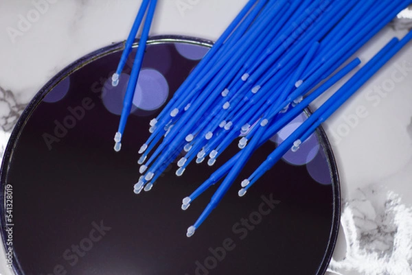 Fototapeta Set of blue microbrushes for eyelashes on a mirror background with bokeh