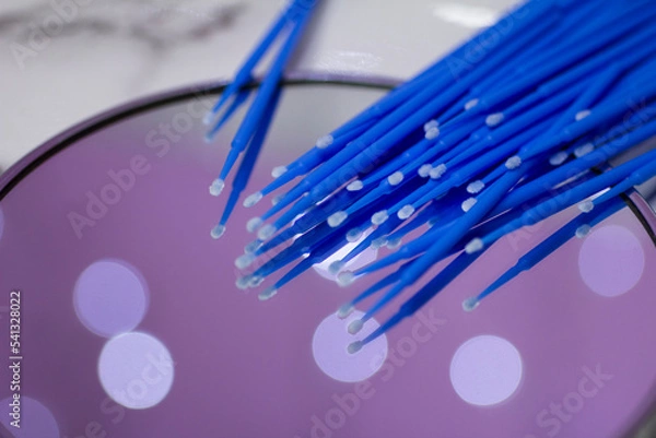 Fototapeta Set of blue microbrushes for eyelashes on a mirror background with bokeh