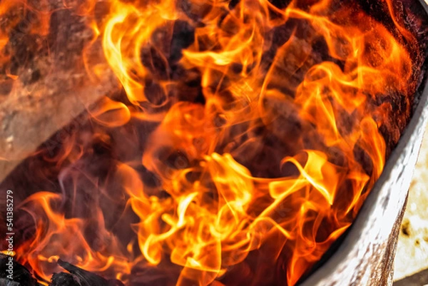 Fototapeta Burning fire close up. Bright orange and red flames on a dark background. Open flame heating. Problems with heating and gas.