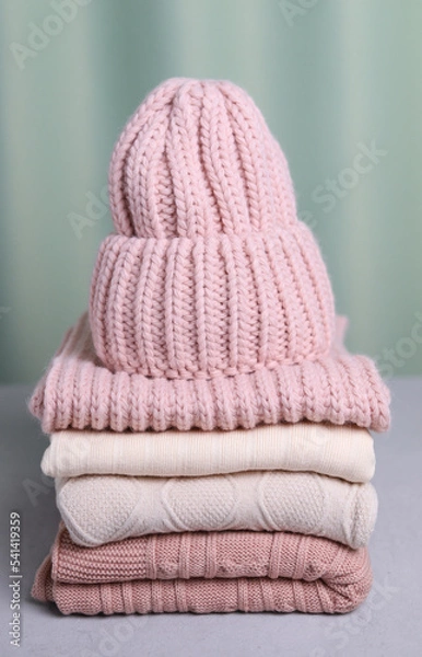 Obraz A knitted hat on a stack of sweaters. Vertical photo. Warming clothes.