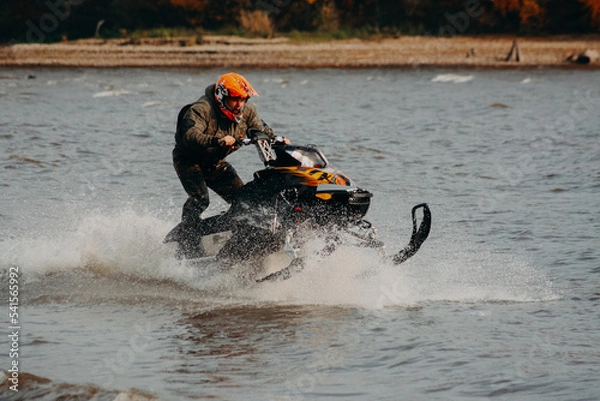 Obraz sportsman on a snowmobile rides on the water