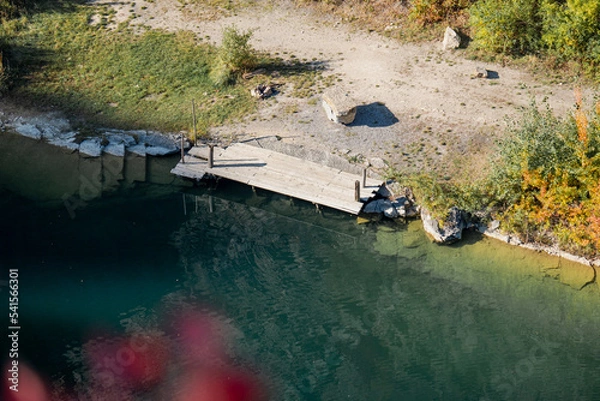 Fototapeta flooded quarry with pier at the bottom