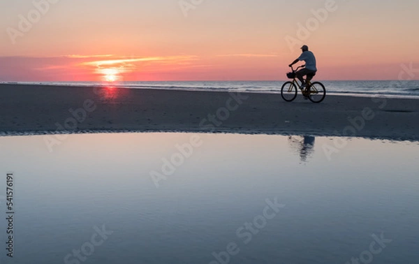Fototapeta Cyclist on the beach at sunrise on Hilton Head Island, South Carolina. 