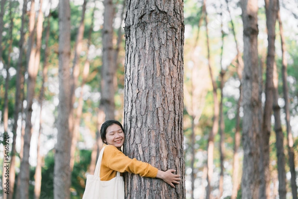 Fototapeta New generation young woman and the big tree in the forest. The environment is of connection sustainable development. renewable energy is environmentally friendly. Technology and new forward.