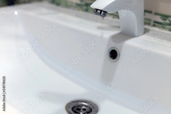 Fototapeta running clean water flows from a tap into a white sink. plumbing