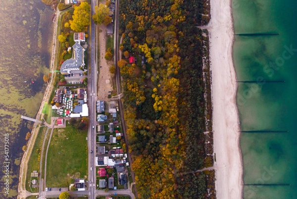Fototapeta drone view of colourful autumn sunset over the village by the baltic sea, chalupy, poland; colourful autumn trees over the sea, sunset over the hel peninsula, baltic sea and puck bay