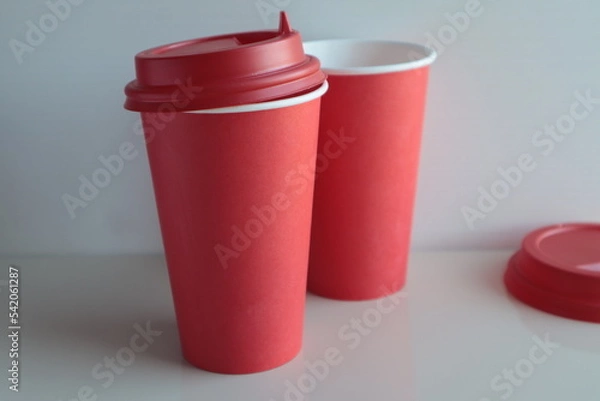 Obraz Red paper disposable cups stand on a light surface.