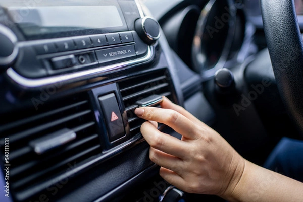Fototapeta Close-up of the hand adjusting the air conditioning button in the car.