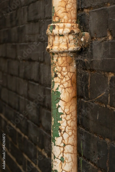 Fototapeta A downpipe in a black brick wall