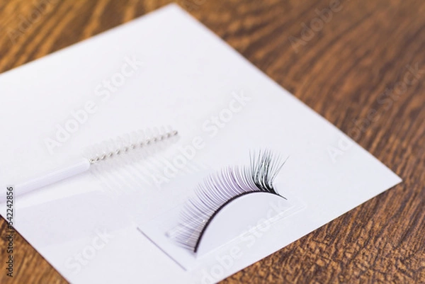 Fototapeta Extensions on artificial eyelashes and an eyelash brush on a white sheet
