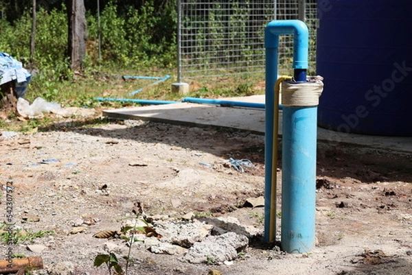 Obraz PVC pipes of underground wells. Rural artesian well with photovoltaic powered submersible pump on dirt terraced background with dry leaves in the countryside. Selective focus