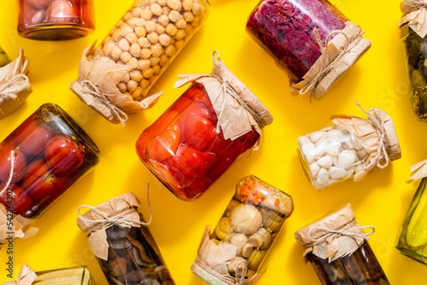 Fototapeta Various kinds preserves vegetables and mushroome in glass jars. Placed on yellow background