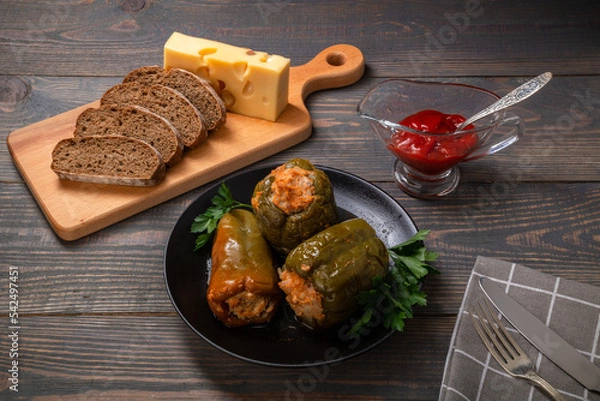 Fototapeta stuffed bell peppers with cheese and sliced bread on a wooden background