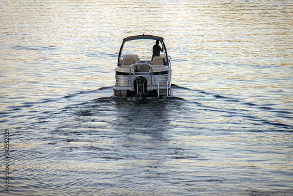 Fototapeta pontoon boat with canopy heading out of the harbor