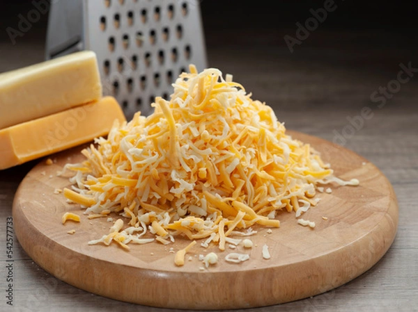 Obraz Shredded mozzarella and red cheddar cheese on wooden cutting board