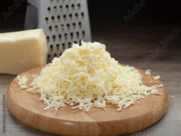 Obraz Shredded mozzarella cheese on wooden cutting board and shredder