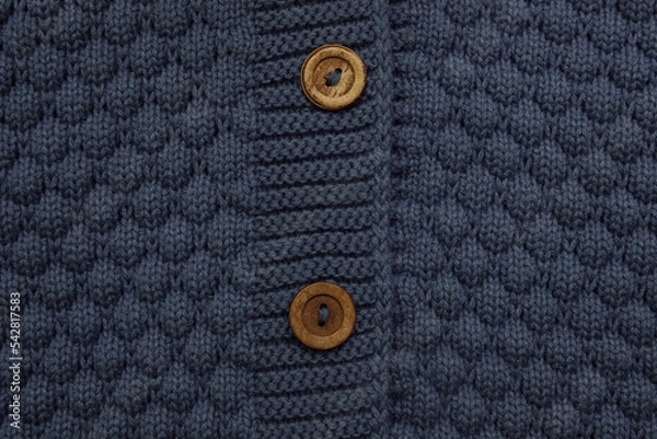 Fototapeta the detail of the sweater fastener with wooden buttons is a close-up of an empty space for text, the concept of warm and natural organic autumn-winter clothing, a template for packaging design.