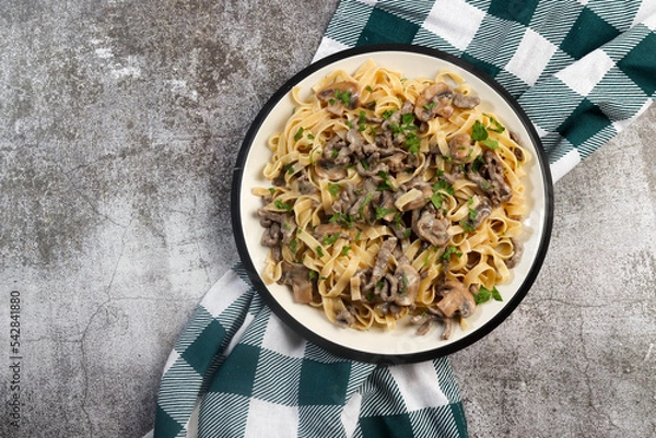 Obraz Homemade Beef Stroganoff Pasta with herbs on a white round plate on a dark grey background. Top view, flat lay