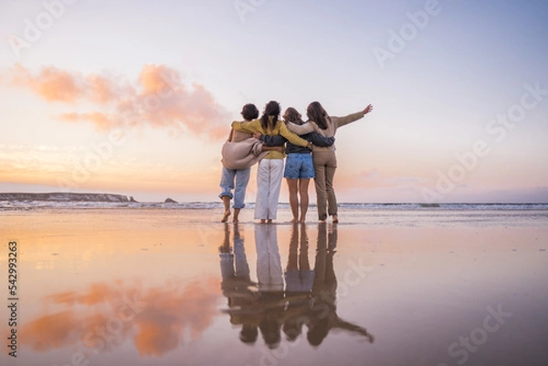 Fototapeta Back view of the four girls embracing and enjoying of the golden sunset at the ocean