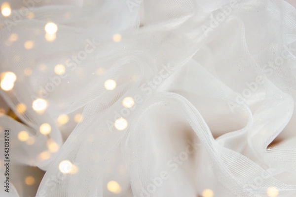 Fototapeta White tulle fabric background with bokeh overlay. Glitter chiffon texture, wedding concept.