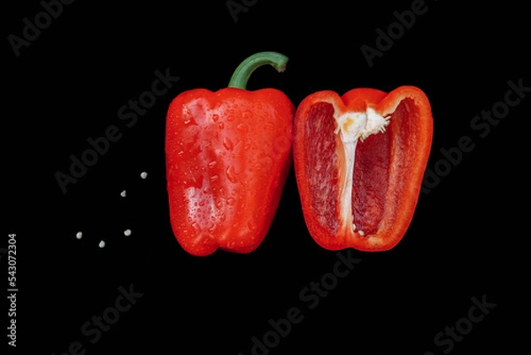 Fototapeta Red bell pepper, paprika cut in half with seeds on a black background close-up with an empty place for text, flatley, organic and healthy food ingredients and vitamins, vegetarianism and farming