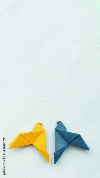 Fototapeta two doves made of origami paper in yellow and blue, in colors of Ukrainian flag on background, vertical, 16:9,