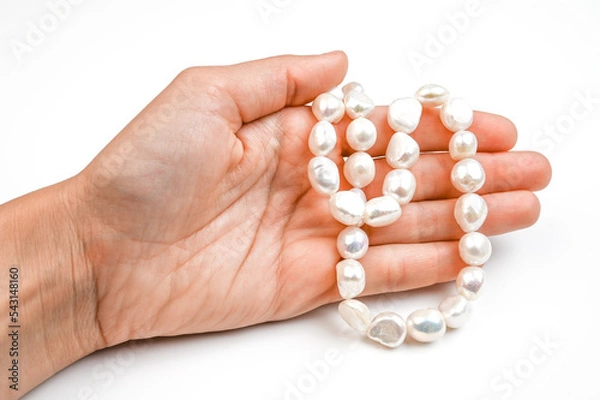 Fototapeta Close up of woman hand with pearl necklace isolated on white. Hand with string of baroque pearls