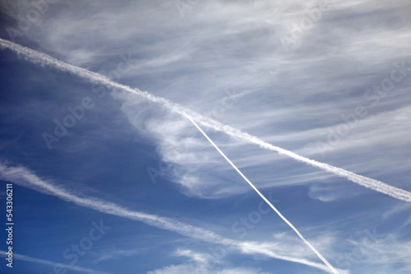 Obraz white trails and some clouds in the blue sky