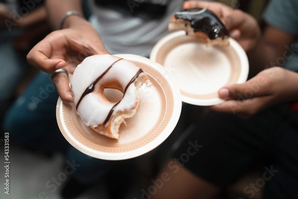 Obraz eating homemade chocolate-dipped and glazed donuts with friends, unrecognizable model