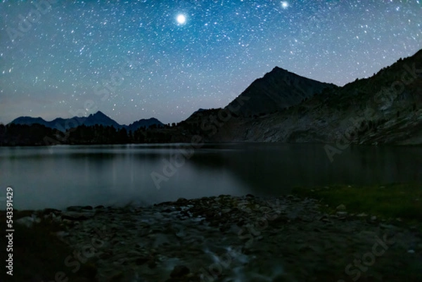 Fototapeta Sapphire Lake in the Cecil D. Andrus-White Clouds Wilderness, part of the Sawtooth National Forest in Idaho, seen on a summer night. A star-filled sky reflects on the surface of the lake.