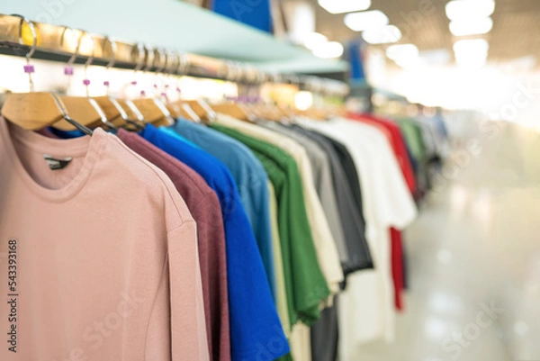 Obraz Clothes on hangers at thrift store or seconhand store. New fashion collection at fashionable clothes store. Clothing rental. Clothes stall against blurred store background with copy space