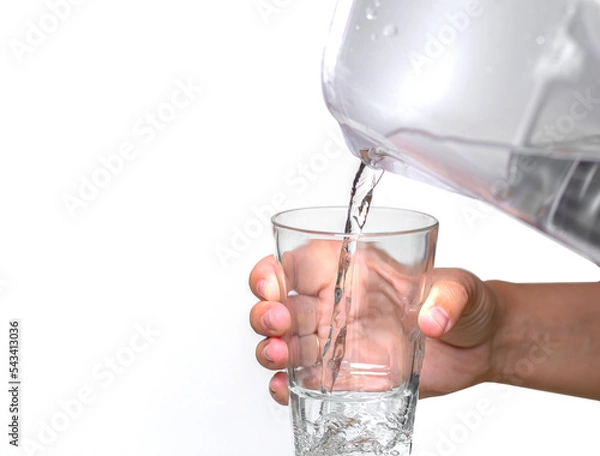Fototapeta Female hands pour clean water from a filter jug into a glass beaker on a white background.