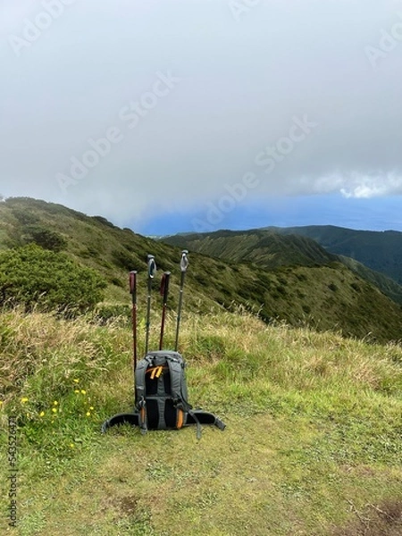 Fototapeta Backpack and hiking sticks on top of a mountain 