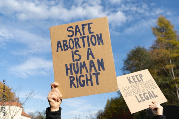 Fototapeta Protesters holding signs with slogans Safe abortion is a human right and Keep abortion legal. People with placards supporting abortion at protest rally demonstration.