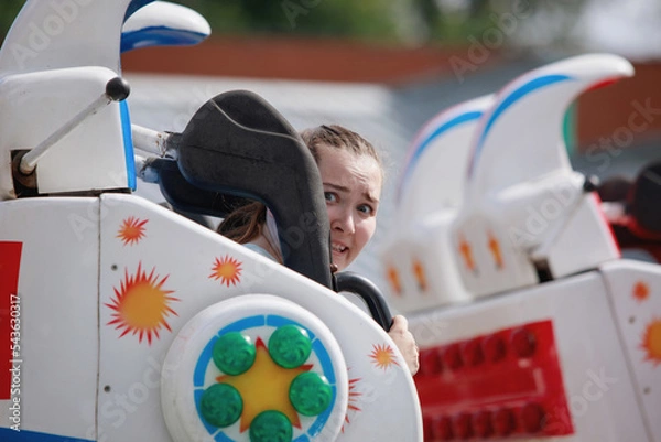 Fototapeta Teenage girls ride on carousels in the park.