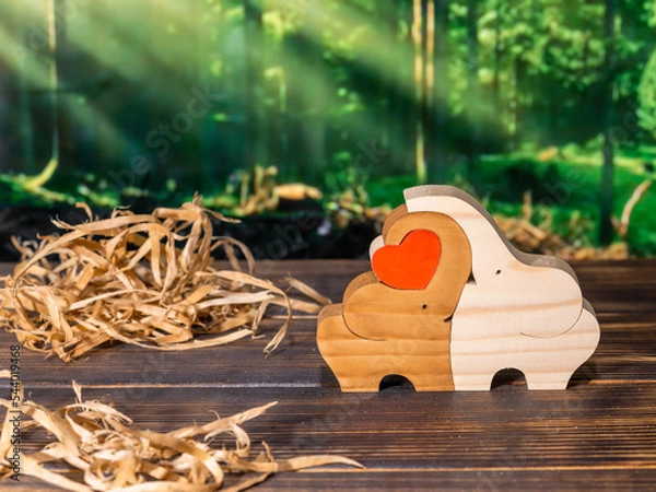 Fototapeta Wooden puzzle in the form of a family of handmade elephants on the background of the forest.