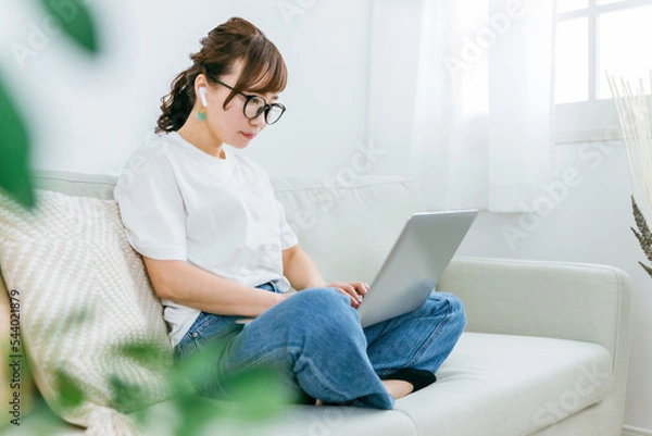 Fototapeta イヤホンを使いながらパソコンを使う日本人女性（音楽・動画）
