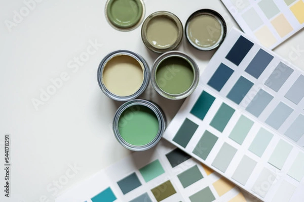 Fototapeta Tiny sample paint cans during house renovation, process of choosing paint for the walls, different green colors, color charts on background