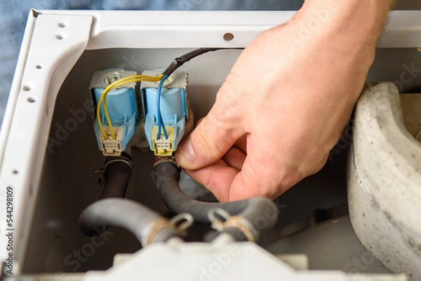 Fototapeta A man is fixing a washing machine. Repairman checks  water inlet valve
