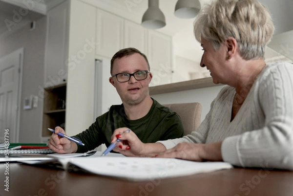 Obraz Caucasian man with down syndrome learning with his mum at home