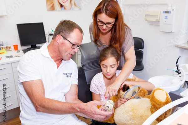 Obraz A doctor explains a young kind how they can care the tooth