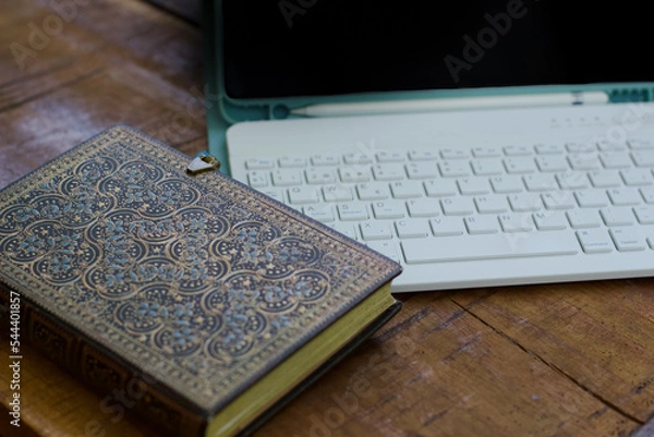 Fototapeta Tablet PC with keyboard, pencil and black screen and a beautiful notebook with and side closure. Material on a wooden table for remote working while traveling. Digital nomad concept.