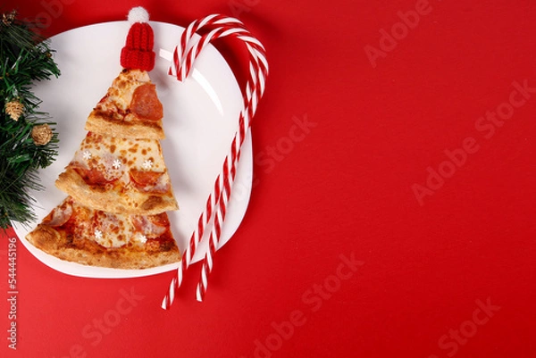 Fototapeta New Year. Christmas. pizza.new year's pizza. pizza chunks are in the shape of a Christmas tree. New Year's composition on a plate.